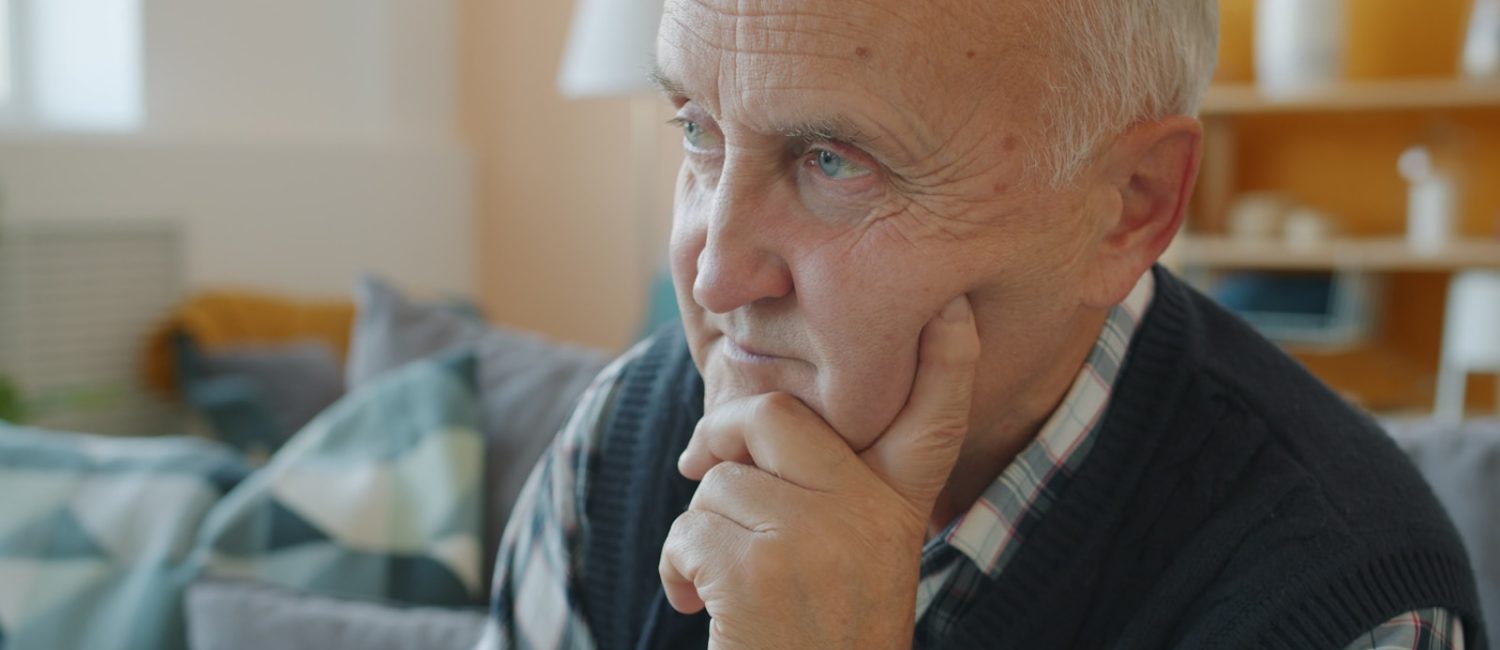 Elderly man with hand on chin, deep in thought.